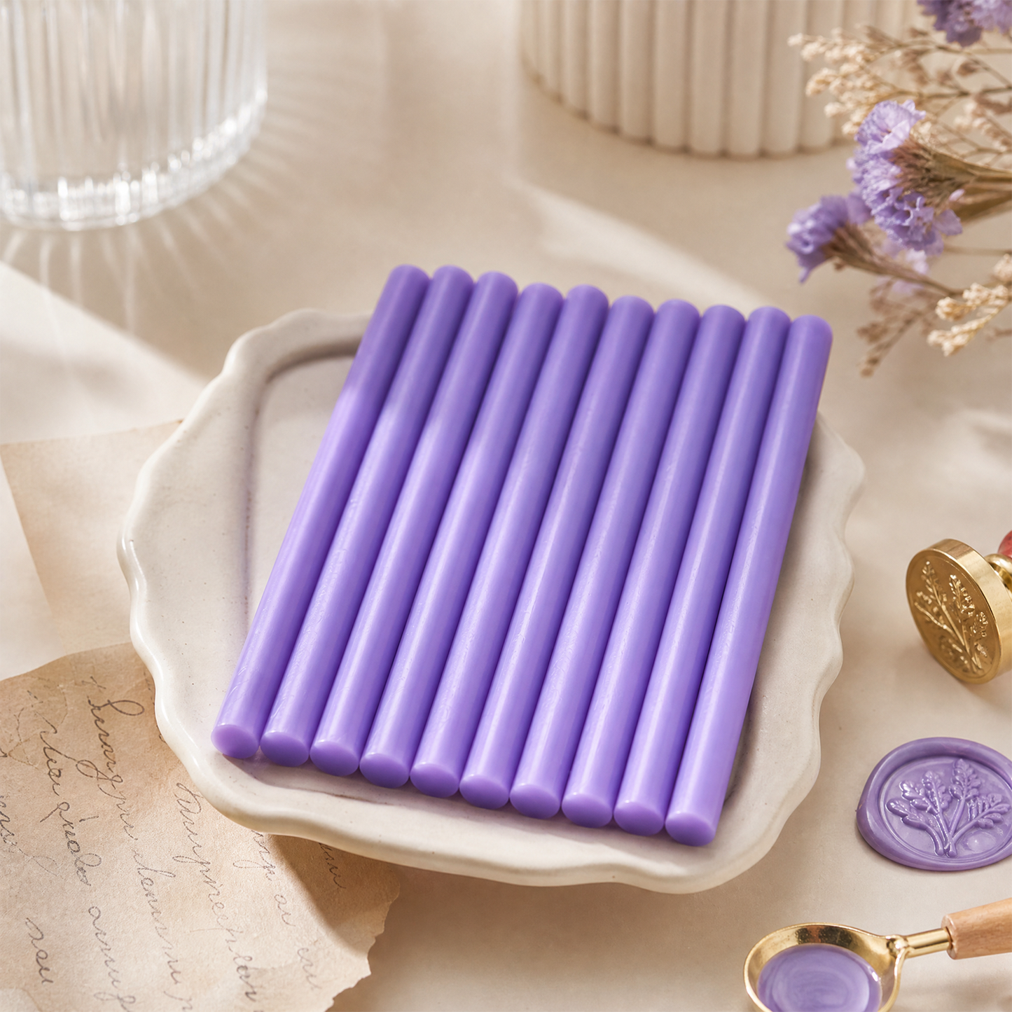 Purple sealing wax sticks on ceramic tray with wax seal stamp and handmade stationery