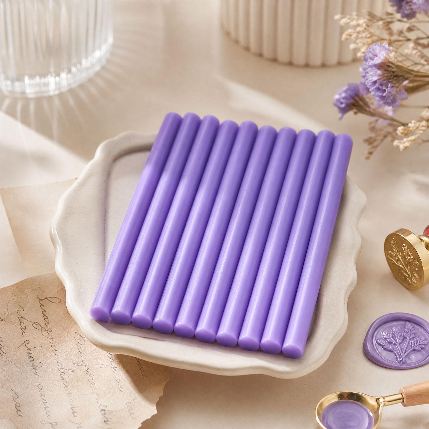 Purple sealing wax sticks on ceramic tray with wax seal stamp and handmade stationery